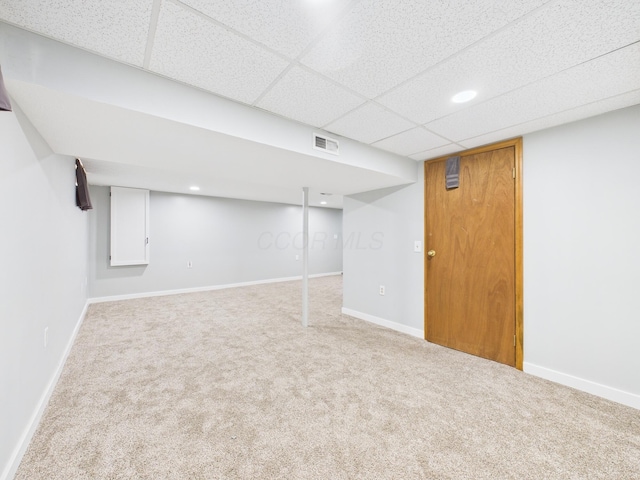 finished basement featuring a paneled ceiling, visible vents, baseboards, and carpet