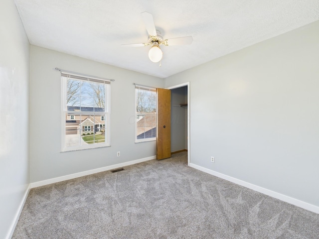 spare room with baseboards, a ceiling fan, carpet flooring, and a textured ceiling