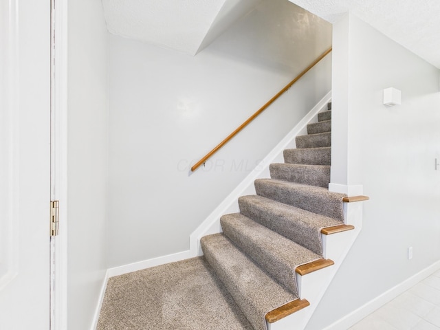 stairway featuring carpet and baseboards