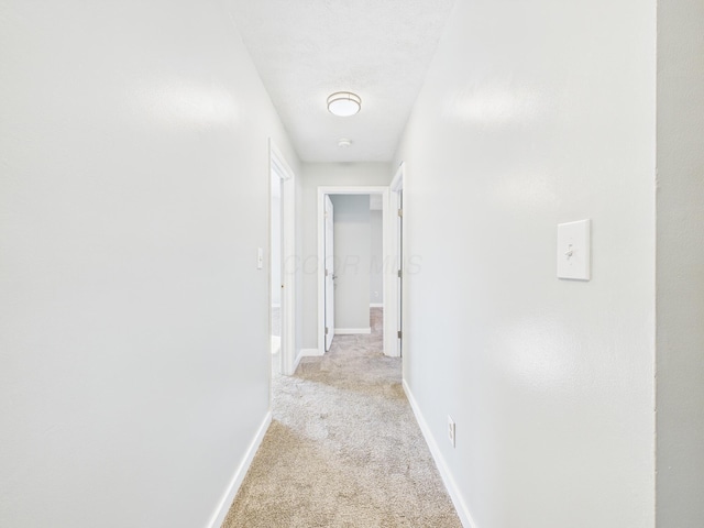 hallway with light carpet and baseboards