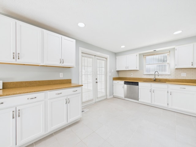 kitchen featuring stainless steel dishwasher, white cabinets, backsplash, and a sink