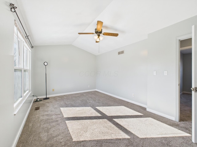 carpeted spare room featuring visible vents, lofted ceiling, baseboards, and a ceiling fan