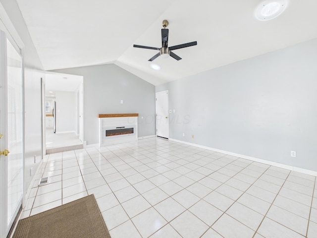 unfurnished living room featuring lofted ceiling, a glass covered fireplace, light tile patterned floors, baseboards, and ceiling fan