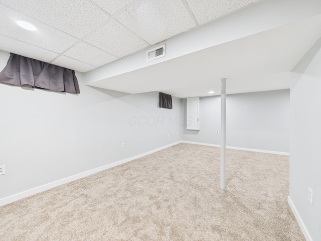 finished below grade area featuring carpet flooring, baseboards, visible vents, and a drop ceiling