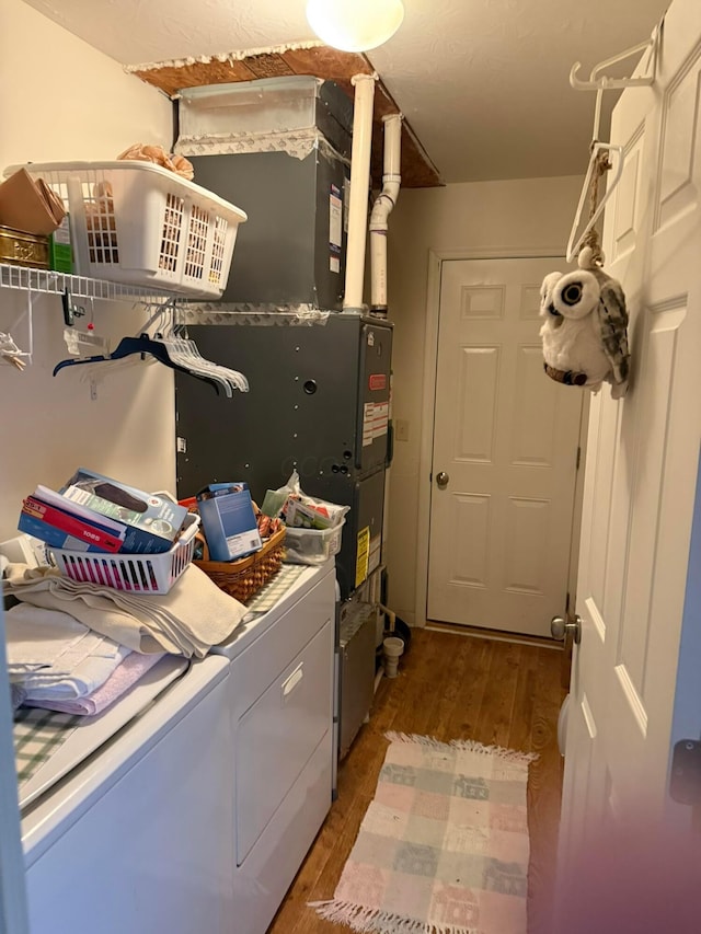 laundry area with laundry area, wood finished floors, and washing machine and clothes dryer