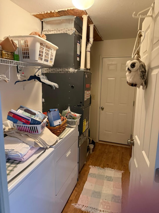 clothes washing area featuring laundry area, wood finished floors, and washer and clothes dryer