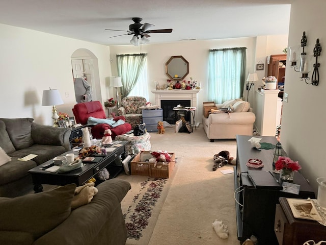 living area with carpet flooring, a fireplace, arched walkways, and ceiling fan