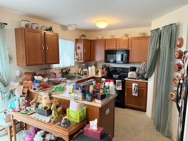 kitchen featuring brown cabinets, black appliances, a sink, a peninsula, and light countertops