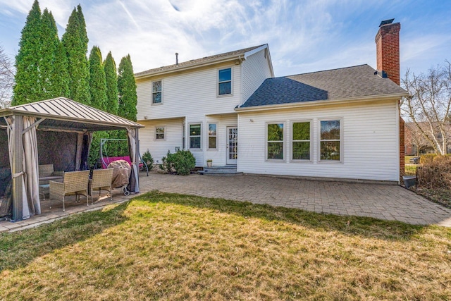 rear view of property featuring a patio, a yard, a chimney, entry steps, and a gazebo