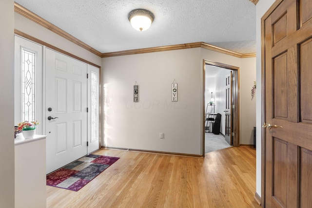 foyer featuring baseboards, a textured ceiling, light wood-style floors, and ornamental molding