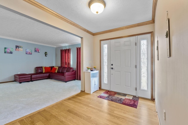 entryway featuring a textured ceiling, plenty of natural light, light wood-type flooring, and ornamental molding