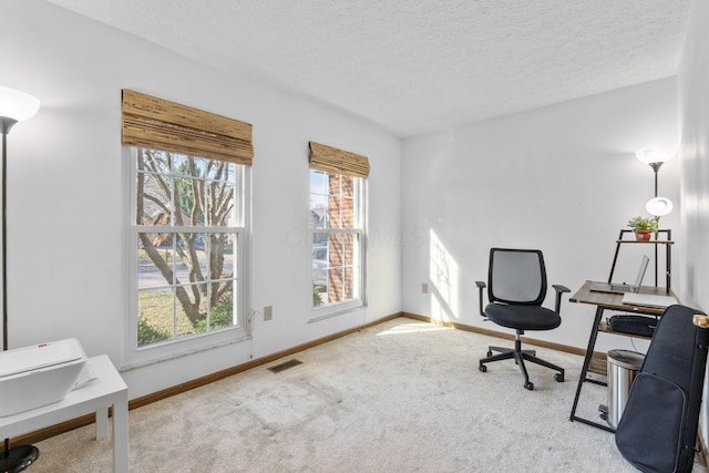 carpeted home office featuring baseboards, visible vents, and a textured ceiling