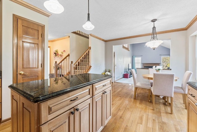 kitchen with open floor plan, a textured ceiling, crown molding, and light wood-style floors