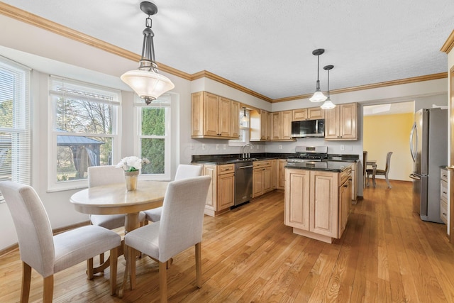 kitchen featuring light brown cabinets, light wood-style floors, appliances with stainless steel finishes, dark countertops, and a center island