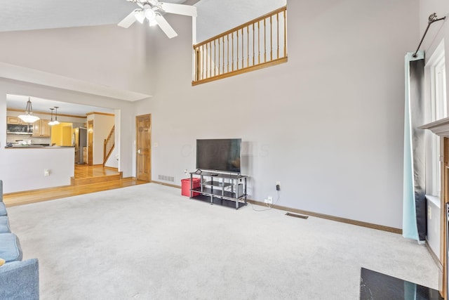 unfurnished living room featuring stairway, light colored carpet, visible vents, and a ceiling fan