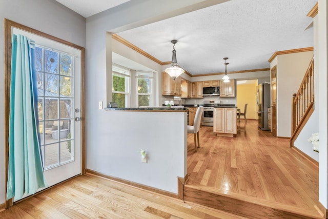 kitchen with a textured ceiling, dark countertops, appliances with stainless steel finishes, and light wood finished floors