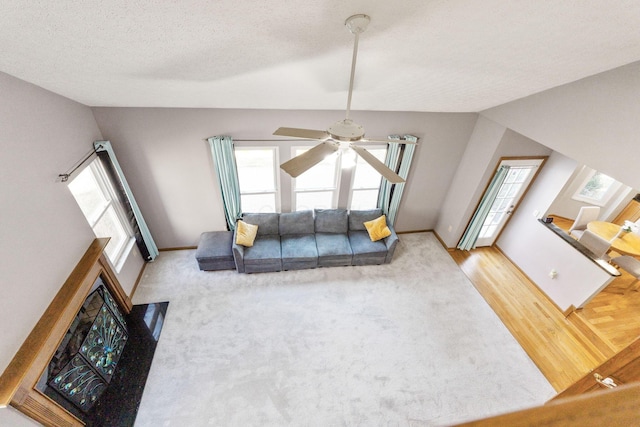 living room with baseboards, lofted ceiling, wood finished floors, a textured ceiling, and a ceiling fan