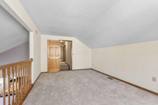 additional living space with lofted ceiling, baseboards, visible vents, and carpet floors