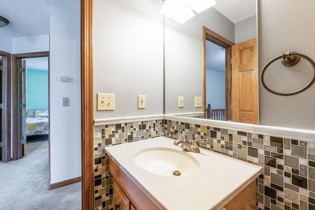 bathroom featuring a textured ceiling, tile walls, wainscoting, and vanity