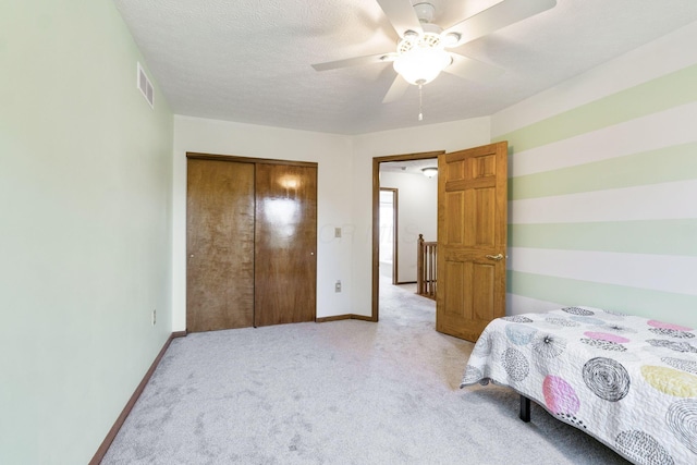 bedroom with visible vents, baseboards, light carpet, a closet, and a textured ceiling