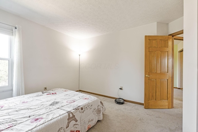 carpeted bedroom featuring a textured ceiling and baseboards