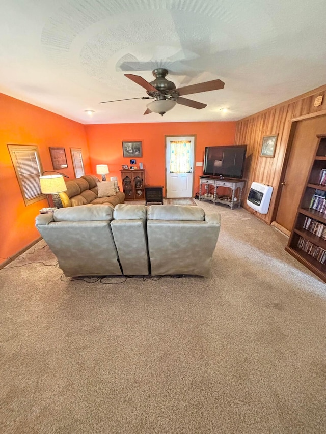 carpeted living area featuring heating unit, a textured ceiling, ceiling fan, and wood walls