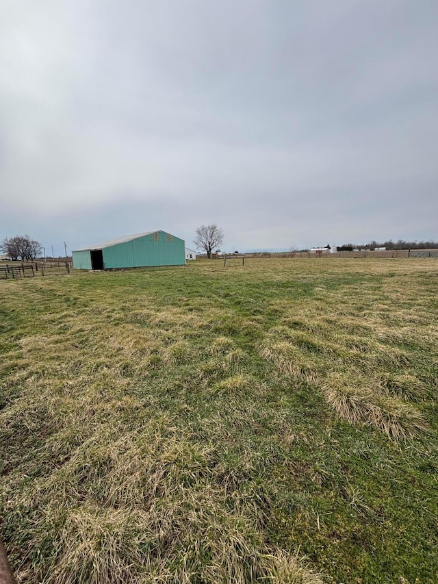 view of yard featuring an outdoor structure, a rural view, and a pole building