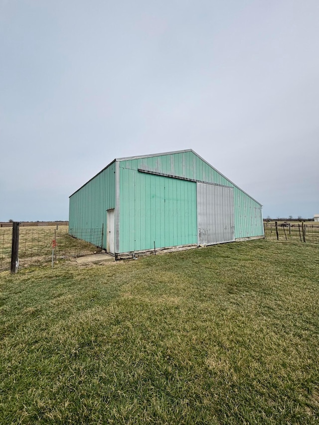 view of pole building featuring a rural view, a lawn, and fence