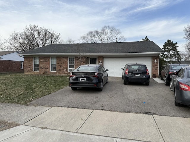 ranch-style home with aphalt driveway, an attached garage, a front yard, and brick siding