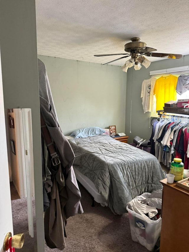 carpeted bedroom with a textured ceiling and a ceiling fan