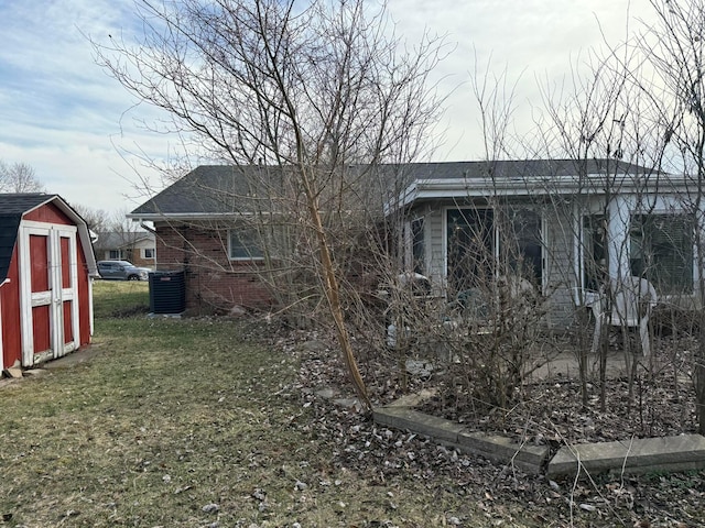 view of home's exterior featuring an outbuilding, a yard, a storage unit, central air condition unit, and brick siding