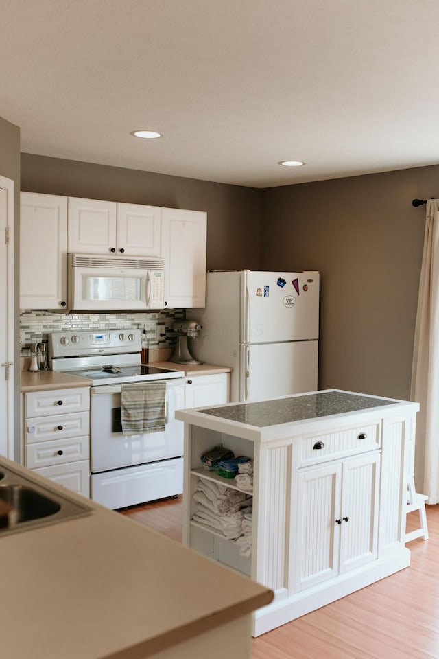 kitchen featuring backsplash, white cabinetry, white appliances, and a center island