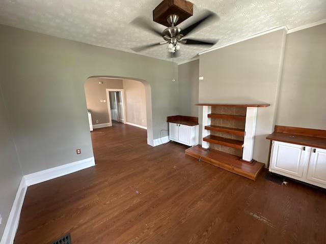 unfurnished room featuring baseboards, ceiling fan, wood finished floors, arched walkways, and a textured ceiling