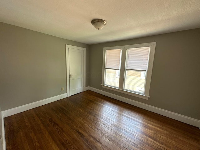 spare room with dark wood finished floors, baseboards, and a textured ceiling