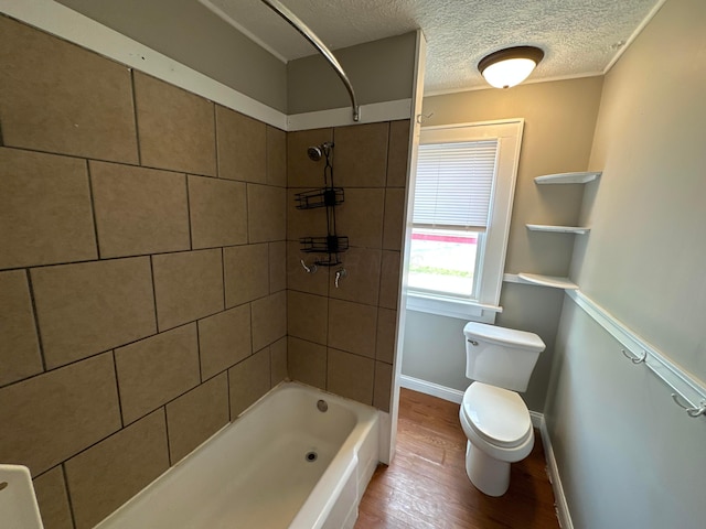 bathroom with toilet, a textured ceiling, wood finished floors,  shower combination, and baseboards