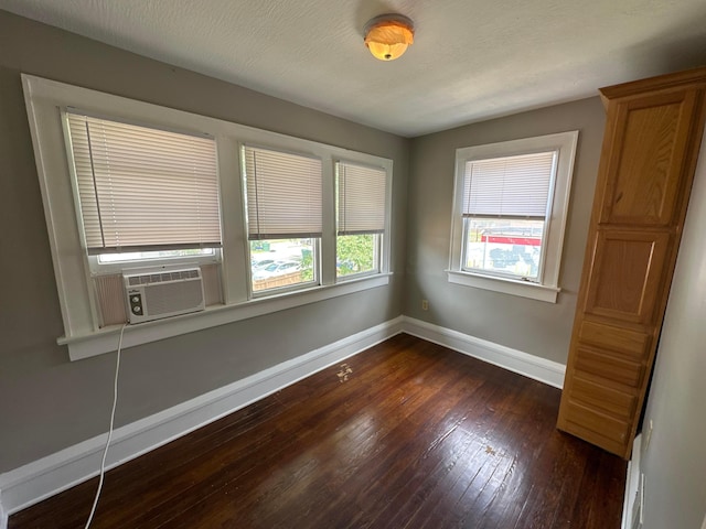 unfurnished room with dark wood-type flooring, cooling unit, baseboards, and a textured ceiling