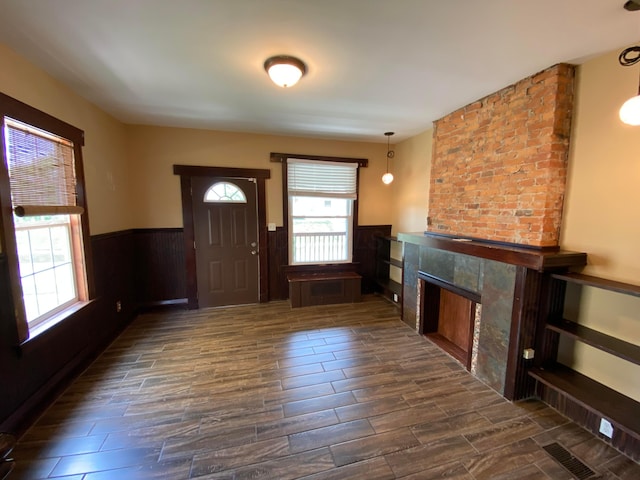 entryway featuring a high end fireplace, a wainscoted wall, dark wood-type flooring, and visible vents