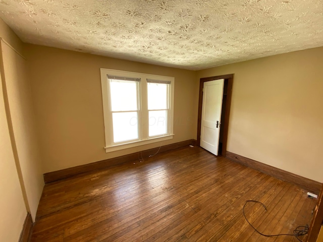 unfurnished room featuring a textured ceiling, baseboards, and dark wood-style flooring