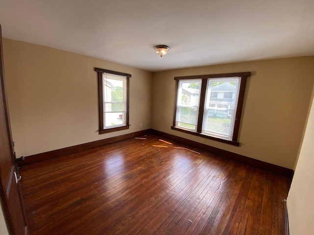 spare room with baseboards and dark wood-style flooring