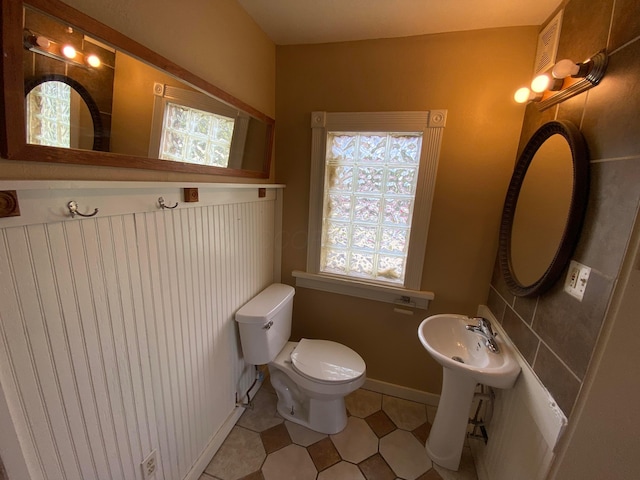 bathroom with a healthy amount of sunlight, toilet, and baseboards