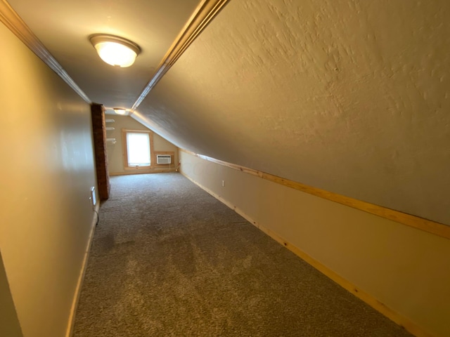 bonus room with baseboards, a wall mounted air conditioner, vaulted ceiling, carpet flooring, and a textured ceiling