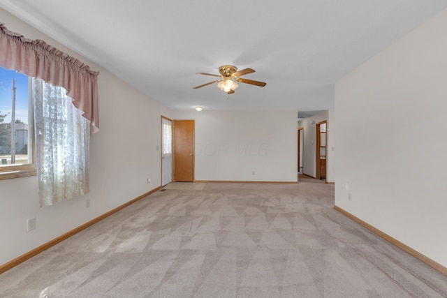 spare room featuring baseboards, light colored carpet, and a ceiling fan