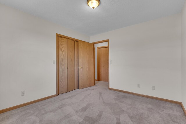 unfurnished bedroom featuring baseboards, a closet, and carpet floors