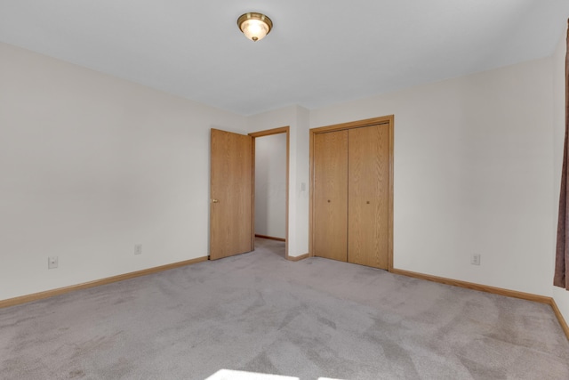 unfurnished bedroom with light carpet, a closet, and baseboards