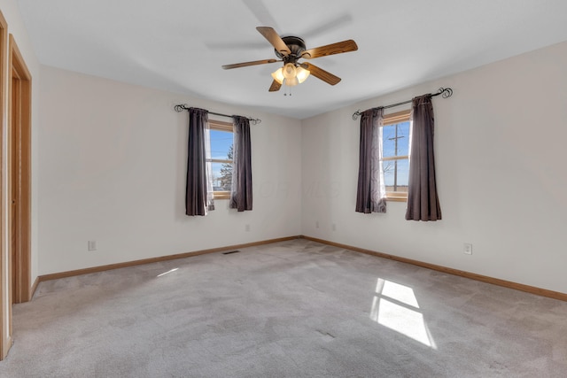 spare room featuring visible vents, baseboards, light colored carpet, and ceiling fan