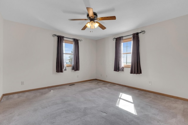 empty room with visible vents, light colored carpet, baseboards, and a ceiling fan