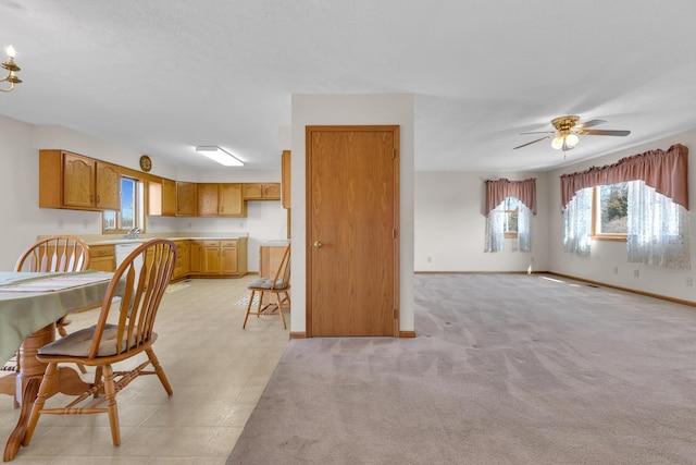 dining area featuring light colored carpet, baseboards, and ceiling fan