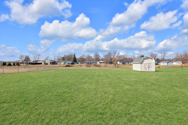 view of yard with a shed, a rural view, an outdoor structure, and fence