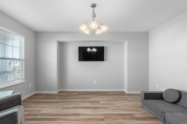 interior space with an inviting chandelier, light wood-style floors, and baseboards