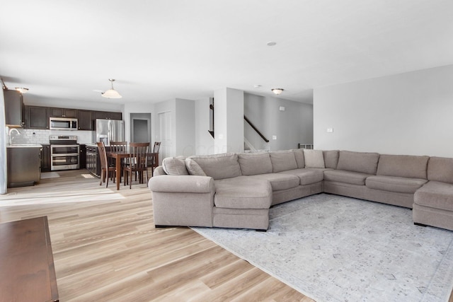 living room featuring stairway and light wood finished floors